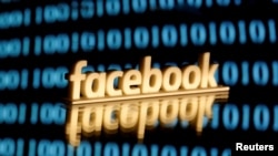 A 3-D printed Facebook logo is seen in front of displayed binary code in this illustration picture.