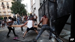 People try to break police barrier during a protest following last week's explosion that killed many and devastated the city, in Beirut, Lebanon, Aug. 11, 2020. 