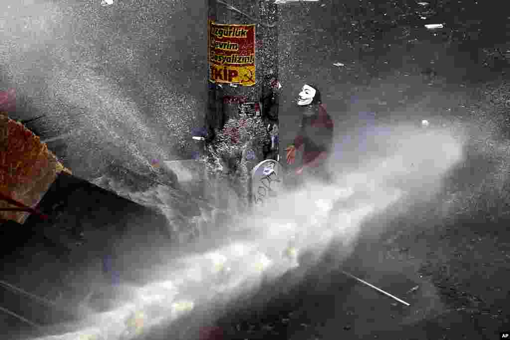 A protester tries to take cover from a water cannon fired by police during clashes in Taksim Square in Istanbul, June 11, 2013.