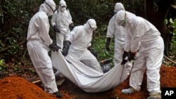 Health workers bury the body of a woman who is suspected of having died of the Ebola virus in Bomi county, on the outskirts of Monrovia, Liberia, Monday, Oct. 20, 2014. 