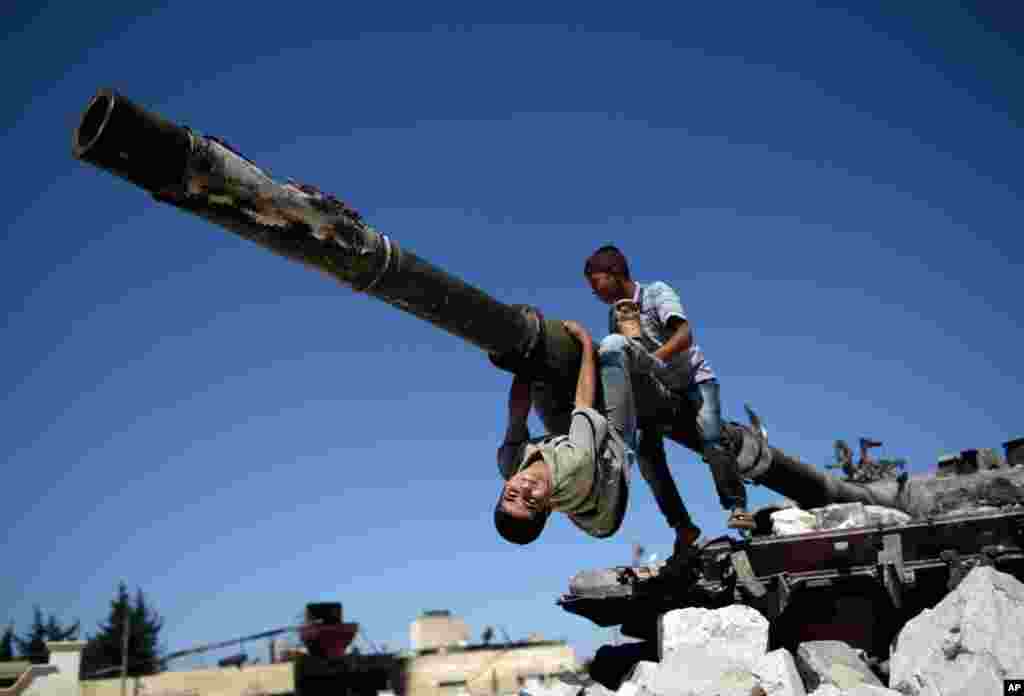 Boys play on a Syrian military tank (destroyed during fighting with the rebels), in Azaz, September 2, 2012. 