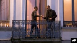 Mohammad Abdeslam, à gauche, frère des auteurs présumés des attaques de Paris, Salah et Brahim Abdelslam, allume des bougies avec un autre homme non identifié au balcon de leur résidence à Molenbeek, Belgique, 18 novembre 2015.