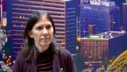 World Wildlife Fund's Mariana Panuncio-Feldman is seen in front of a photo of Pittsburg, one of the U.S. cities committed to drastically cutting climate emissions. (Lisa Bryant/VOA)