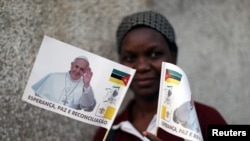 A women poses with flags bearing the face of Pope Francis outside a Catholic church in Lhanguene, Maputo, Mozambique, Aug. 31, 2019.