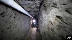 FILE - Federal Police officer stands in the tunnel where drug lord Joaquin "El Chapo" Guzman made his escape from the Altiplano maximum security prison in Almoloya, west of Mexico City, July 16, 2015.