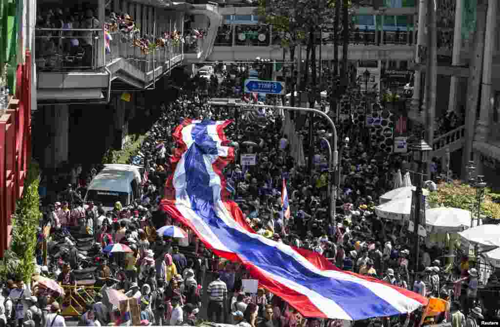 Para pengunjuk rasa anti-pemerintah berbaris dengan membawa bendera Thailand raksasa di distrik perbelanjaan di pusat kota Bangkok (13/1). (Reuters/Nir Elias)
