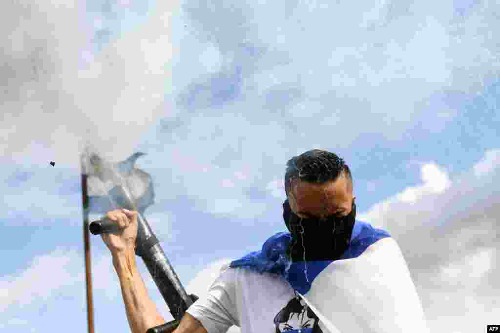 An anti-government demonstrator fires a homemade mortar in Managua, Nicaragua demanding justice for the death of six members of a single family who died when their house was burnt.