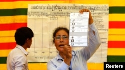FILE - An election official shows a ballot paper in Phnom Penh, July 28, 2013. 