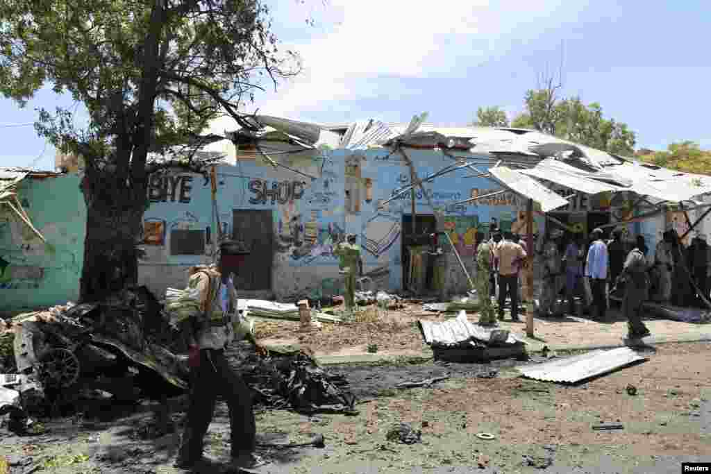 A police officer walks at the scene of a suicide car bomb attack next to a cafe in the suburbs of Mogadishu, Feb. 27, 2014.