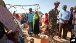 FILE - Somalia Conflict takes toll on civilian mental health. A Somali soldier provides security as newly displaced Somalis gather at a camp on the outskirts of Mogadishu, Somalia, March 28, 2017. 