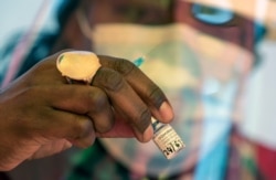 FILE - A health worker prepares a dose of the Pfizer coronavirus vaccine at the newly-opened mass vaccination program for the elderly at a drive-thru vaccination center in Johannesburg, South Africa, May 25, 2021.