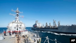 FILE - Guided-missile destroyer USS Bulkeley participates in a replenishment-at-sea with fleet replenishment oiler USNS John Lenthall in the Gulf of Oman. Iranian naval vessels conducted rocket tests last week near the USS Harry S. Truman aircraft ca