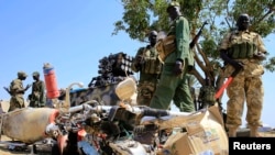 South Sudan soldiers stand next to a destroyed motorcycle near Bor Airport, northwest of Juba, Dec. 25, 2013. 
