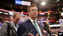 FILE - Then-Trump campaign Chairman Paul Manafort talks to reporters on the floor of the Republican National Convention, in Cleveland, Ohio, July 17, 2016. Rick Gates is seen in the background, at left.