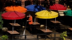 FILE - A worker wearing a mask to protect against the coronavirus power-washes an exterior dining area along the River Walk, in San Antonio, Texas, Aug. 12, 2020.