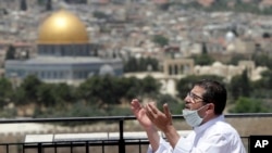 A muslim man prays in east Jerusalem's Mount of Olives, overlooking the Dome of the Rock and al-Aqsa mosque compound, which remains shut to prevent the spread of coronavirus during the holy month of Ramadan, May 22, 2020. 