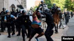 FILE - Riot police chase a man as they rush protesters to clear Lafayette Park and the area around it across from the White House for President Donald Trump to be able to walk through for a photo opportunity in front of St. John's Episcopal Church, June 1