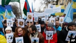 FILE - Ukrainian and Crimean Tatar activists hold portraits with the names of victims of the Russian annexation of Crimea, during a rally in Kyiv, Ukraine, Feb. 26, 2017.
