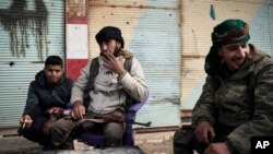 U.S.-backed Syrian Democratic Forces (SDF) fighters sit outside a building as fight against Islamic State militants continue in the village of Baghouz, Syria, Feb. 16, 2019.