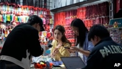 ឈ្មួញ​ថត​ផលិតផល​គ្រឿងអលង្ការ​របស់​ពួកគេ​សម្រាប់​ការ​លក់​តាម​ប្រព័ន្ធ​អេឡិចត្រូនិក​នៅ​ហាង​របស់​ពួកគេ​នៅ​ក្នុង​ទីផ្សារ​លក់ដុំ Yiwu ក្នុង​ក្រុង Yiwu ខេត្ត Zhejiang ភាគ​ខាងកើត​ប្រទេស​ចិន កាលពី​ថ្ងៃ​សុក្រ ទី៨ ខែវិច្ឆិកា ឆ្នាំ២០២៤។