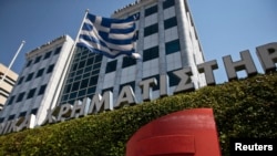 Sebuah bendera Yunani berkibar di depan Gedung Bursa Saham Athena (Foto: dok) .