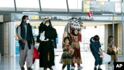 Families evacuated from Kabul, Afghanistan, walk through the terminal before boarding a bus after they arrived at Washington Dulles International Airport, in Chantilly, Virginia.