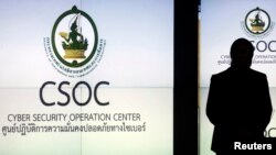 FILE - A man is silhouetted against a screen at the Cyber Security Operation Center in Bangkok.