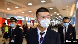 FILE - China Eastern Airlines flight crew wear protective masks on arrival at Sydney International Airport in Sydney, Australia, Jan. 23, 2020. (AAP Image/Joel Carrett/via Reuters) 