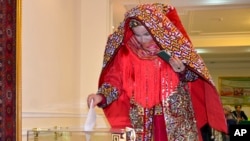 A Turkmen woman dressed in traditional costume casts her ballot at a polling station in Ashgabat, Turkmenistan, Feb. 12, 2017.