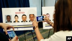 FILE -Reporters photograph wanted posters of people facing criminal charges before a news conference in Washington, June 15, 2017, about the May 16, 2017 altercation outside the Turkish Embassy in Washington during the visit of the Turkish president. 
