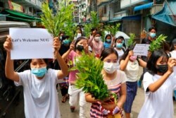 Anti-coup protesters hold leaf branches and signs to welcome the NUG, or National Unity Government, as they march April 17, 2021, in Yangon, Myanmar.