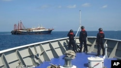 FILE - In this April 27, 2021, photo provided by the Philippine coast guard, its personnel patrol beside ships said to be Chinese militia vessels at Sabina Shoal in the South China Sea. The Philippines said on May 11, 2024, China is building "an artificial island" at the shoal.