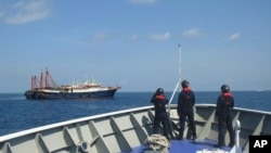 Anggota pasukan dari Filipina melakukan pengawasan di sebelah kapal yang disinyalir sebagai kapal milisi China di Sabina Shoal di Laut China Selatan. (Foto: via AP)