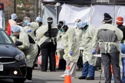 A caregiver tests a patient for coronavirus at University Hospitals, Monday, March 16, 2020, in Mayfield Heights, Ohio.