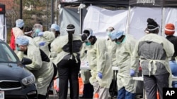 A caregiver tests a patient for coronavirus at University Hospitals, Monday, March 16, 2020, in Mayfield Heights, Ohio.