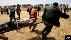 Palestinian protesters and civil defense evacuate a wounded youth during clashes with Israeli troops along Gaza's border with Israel, east of Khan Younis, April 6, 2018. 