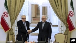 Menteri Luar Negeri Iran Mohammad Javad Zarif (kanan) berjabat tangan dengan utusan PBB-Liga Arab untuk Suriah Lakhdar Brahimi pada konferensi pers di Tehran (26/10).