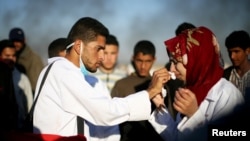Female Palestinian medic Razan Al-Najar reacts to tear gas as she works at the scene of clashes at Israel-Gaza border, in the southern Gaza Strip, April 1, 2018.