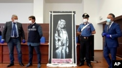 Italian authorities unveil a stolen artwork painted by the British artist Banksy as a tribute to the victims of the 2015 terror attacks at the Bataclan music hall in Paris, during a press conference in L' Aquila, Italy, June 11, 2020.