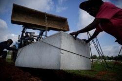 Willie Johnson, 66, left, Horace Bell, 60, center, and Eugene Davis, 58, right, lower a burial vault into a grave at Cedar Hill Cemetery on April 18, 2020, in Dawson, Ga.