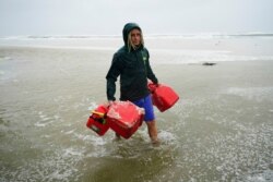 A man carries empty fuel containers in Gulf Shores, Ala., Sept. 15, 2020.