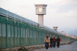 FILE - Workers walk the perimeter fence of what is officially known as a vocational skills education center in Dabancheng in Xinjiang Uighur Autonomous Region, China, Sept. 4, 2018.
