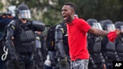 FILE - A protester yells at police in front of the Baton Rouge Police Department headquarters after police arrived in riot gear to clear protesters from the street in Baton Rouge, Louisiana, July 9, 2016.
