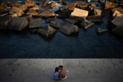 A couple kisses as they sit by the sea in Barcelona, Spain, Saturday, July 25, 2020.