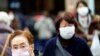 FILE - Pedestrians wear protective masks in Tokyo, Jan. 16, 2020. Japan's government said a man treated for pneumonia after returning from China has tested positive for the new coronavirus identified as a possible cause of an outbreak in Wuhan, China.