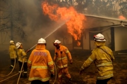 FILE - Firefighters battle the Morton Fire as it burns a home near Bundanoon, New South Wales, Australia, Jan. 23, 2020. (AP Photo/Noah Berger)