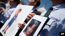 FILE - Fathers who lost their children to spousal abduction to Japan hold photos of their children during a news conference on Capitol Hill in Washington, May 5, 2010 In 2013, Japan’s parliament approved joining the 1980 Hague Convention on international child abduction, a global child custody treaty, amid foreign concerns that Japanese mothers can take children away from foreign fathers without recourse. 