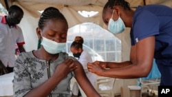 A nurse administers an AstraZeneca vaccination against COVID-19, at a district health center giving first, second, and booster doses to eligible people, in the low-income Kibera neighborhood of Nairobi, Kenya, Jan. 20, 2022. 