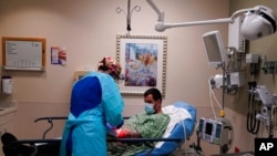FILE - Registered nurse Jana Kendall tends to a COVID-19 patient in an emergency room at Mission Hospital in Mission Viejo, Calif., Dec. 21, 2020. 