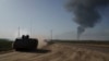 Soldados israelíes avanzan en un vehículo blindado cerca de la frontera con la Franja de Gaza mientras una columna de humo se observa desde el territorio palestino el 21 de enero de 2024.